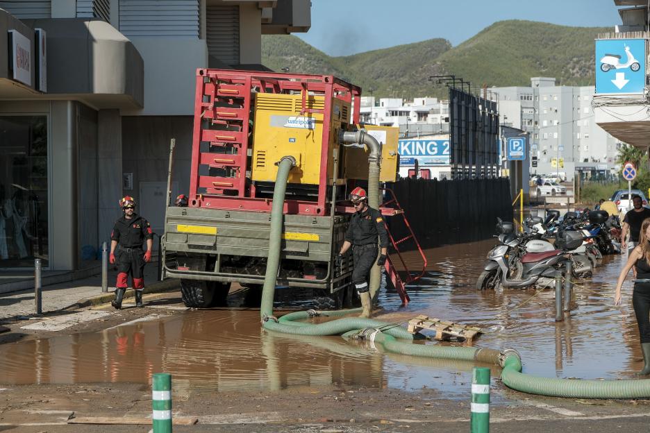 Firefighters use a large pump to remove floodwater from a street in Ibiza, Spain.