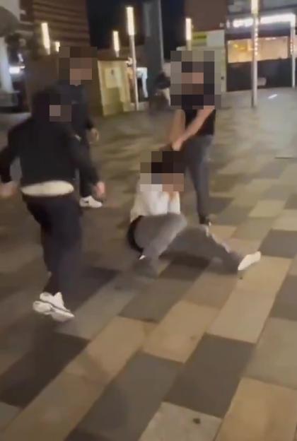 Three individuals attacking one person who is on the ground.