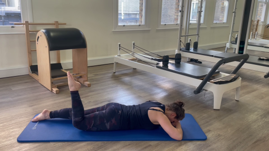 Woman performing a Pilates leg exercise.