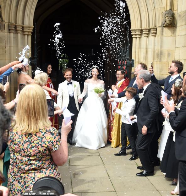 Newlyweds leaving a ceremony, showered with confetti.