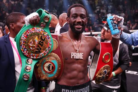 Terence Crawford holding championship belts after a boxing match.