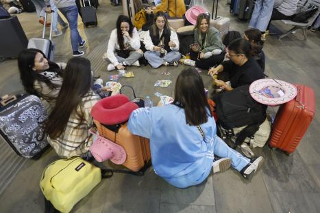 Passengers playing cards at a train station.