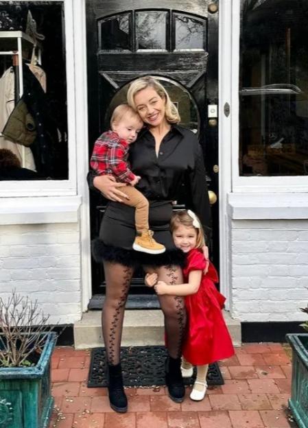 Kelsey Parker holds her son and daughter in front of a doorway.