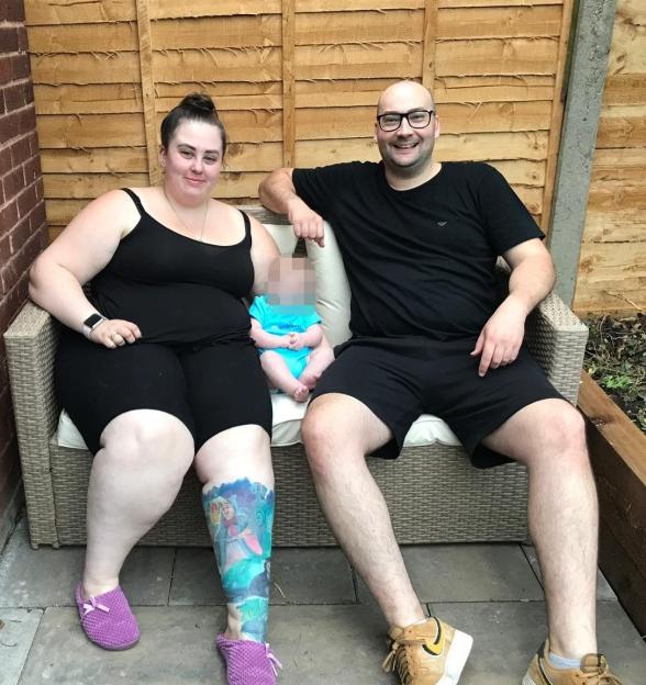 A woman, man, and baby sitting on a patio couch.