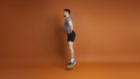 Man mid-jump during at-home workout.