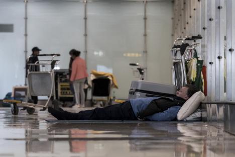 Person sleeping on the floor of an airport terminal.