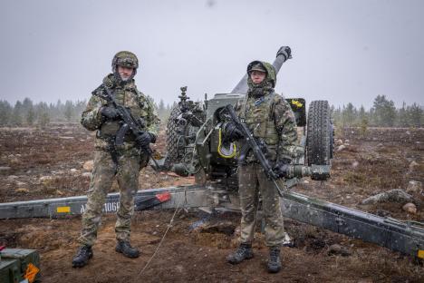 Two Finnish conscripts standing by an artillery piece during a NATO exercise.