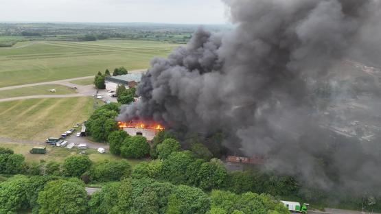 Aerial view of a large fire and thick black smoke at Bicester Motion.