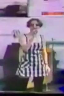 Woman in black and white striped dress singing.