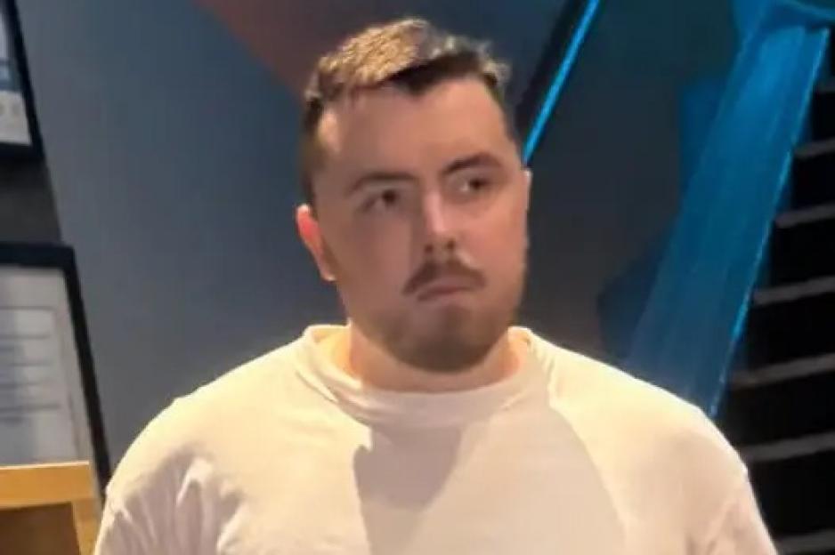 A man with a beard and mustache wearing a white shirt looks to the right.