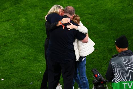Ange Postecoglou embracing his family on the field after a game.
