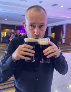 Man holding two pints of Guinness.