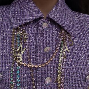 Purple sequined jacket with layered necklaces.
