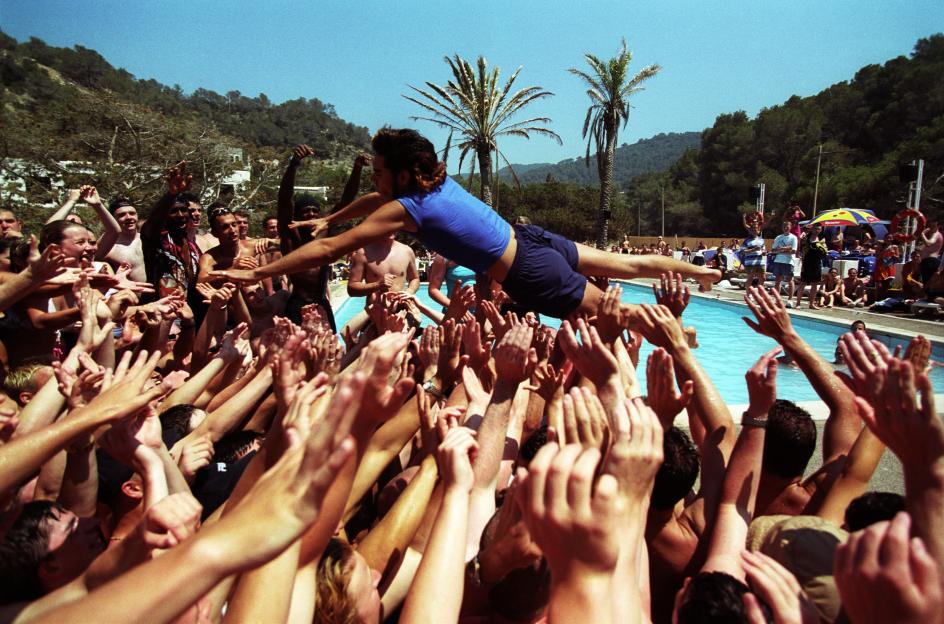 Person being tossed into the air by a crowd of people at a pool party.