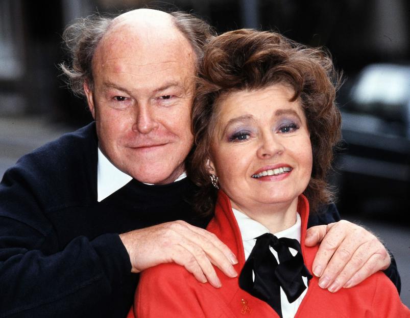 A man and woman are posing for a picture, and the woman is wearing a red jacket