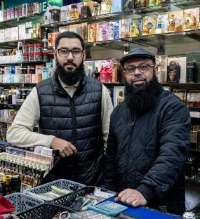 Portrait of a father and son, retail owners, in their perfume shop.