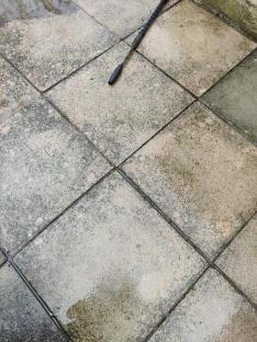 Pressure washer wand on a dirty patio.