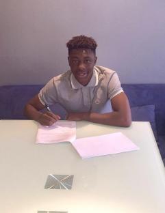 Young man signing a document at a table.