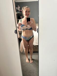 Woman in a swimsuit taking a selfie in a mirror.