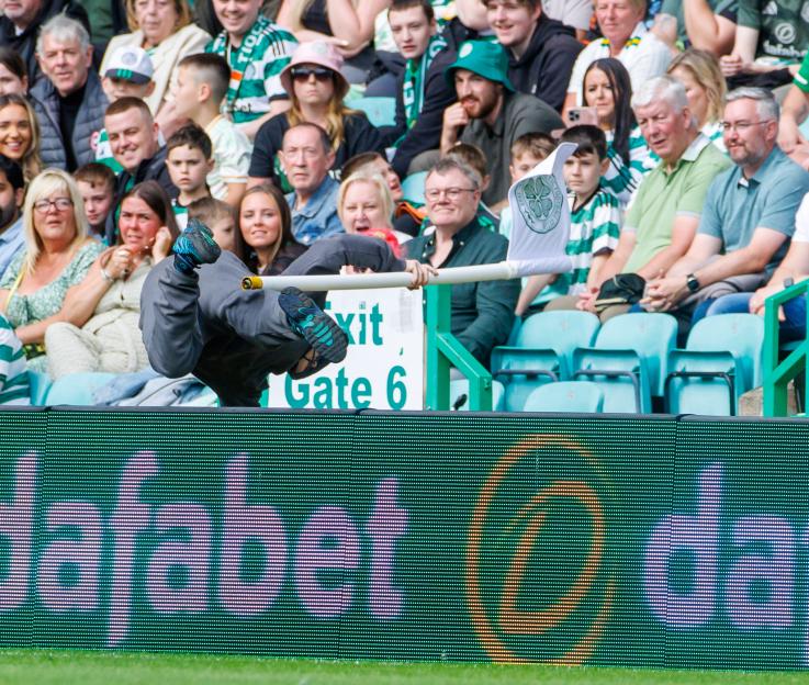 A pitch invader running away with a corner flag at a soccer game.