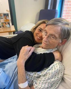 Woman hugging her father in a hospital bed.