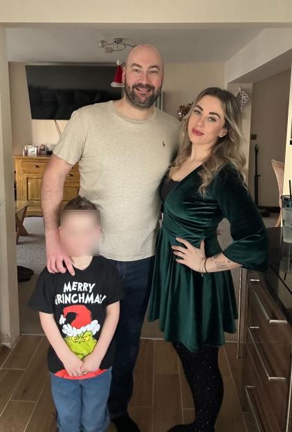 A woman, man, and child pose for a photo in their kitchen.