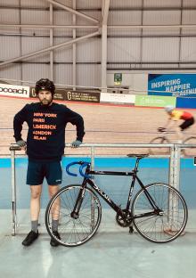 Man standing with his bike at a velodrome.