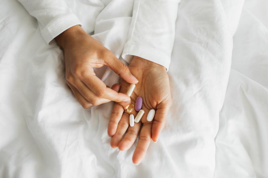Person holding various pills in their hand.