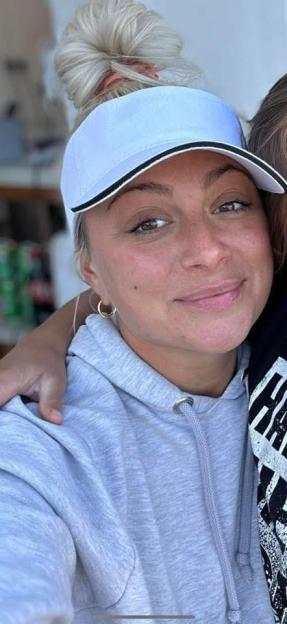Close-up of a woman wearing a light blue visor and a gray hoodie.