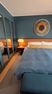 Graham Norton's New York bedroom with teal walls, a large iris print, and a blue bed.