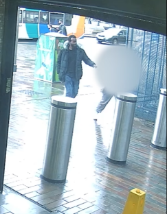 Surveillance image of a man walking near a bus stop.