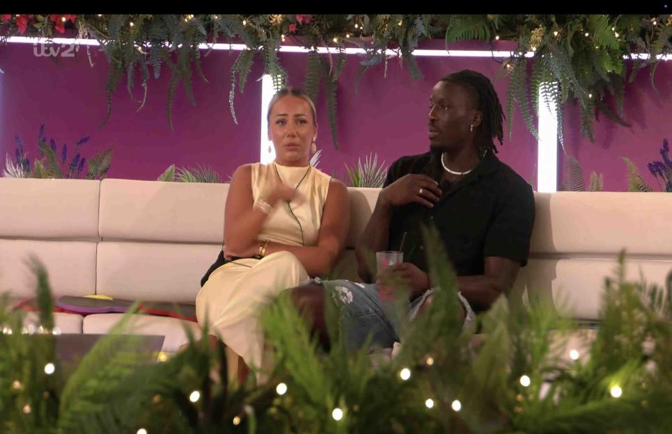 Meg and Dejon from Love Island sitting on a couch.
