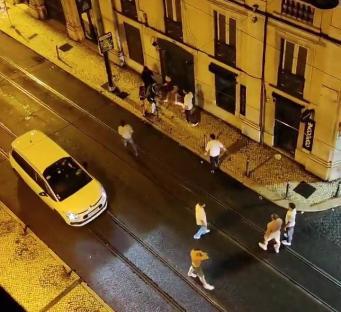 Nighttime street scene showing a group of people near a building, a yellow car, and a stabbing incident.