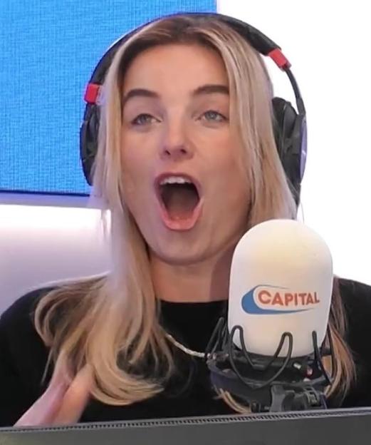 A blonde woman in black headphones with her mouth open wide, next to a microphone with the "CAPITAL" logo.