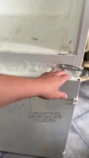 A hand reaches into a very dirty freezer.