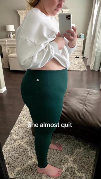 A woman in a white sweatshirt and green leggings takes a mirror selfie, with text overlay "She almost quit".