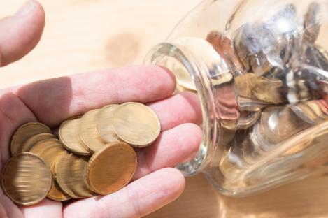 Hand taking coins from a glass jar.