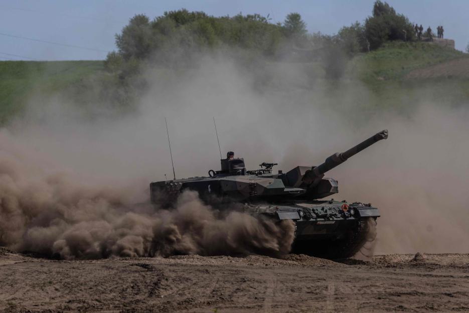 Leopard tank kicking up dust during military exercise.