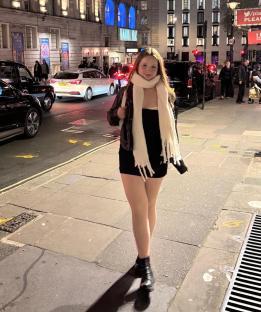 Teenage girl walking down a city street at night.