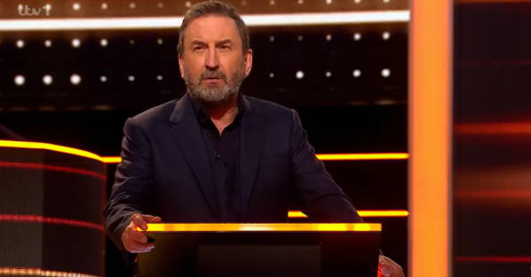 A man in a suit hosting a game show.