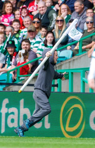 Person running with a corner flag at a soccer match.