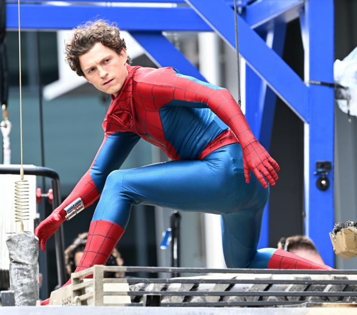 Tom Holland in a Spider-Man suit on a film set.