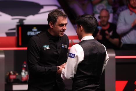 Ronnie O'Sullivan and Zhao Xintong shaking hands after a snooker match.