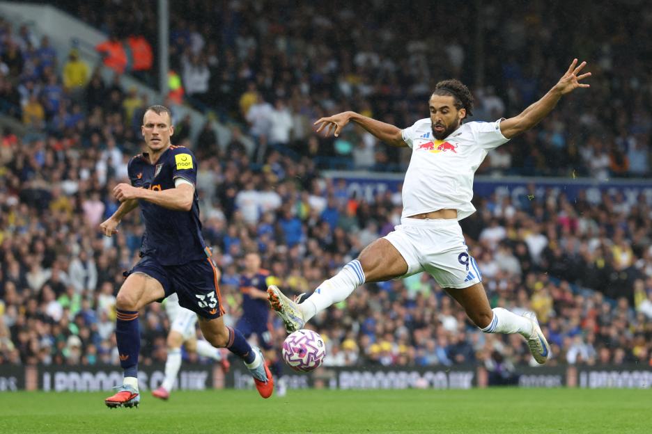 Soccer player controls the ball under pressure from a defender.