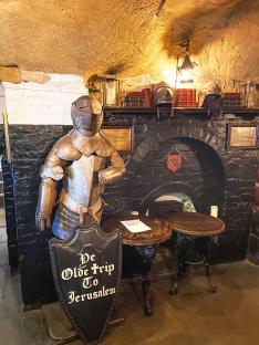 Interior of Ye Olde Trip to Jerusalem Inn, featuring a suit of armor and pub tables.