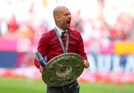 Pep Guardiola celebrating with the Bundesliga championship trophy.