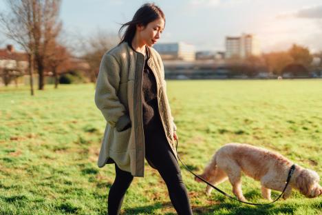 Woman walking her Goldendoodle in a park.