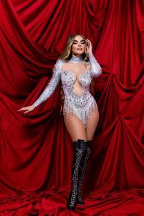 Melody, representing Spain, in a sparkling silver bodysuit and black boots against a red backdrop.
