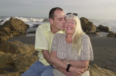 A man kissing a woman on the cheek at the beach.