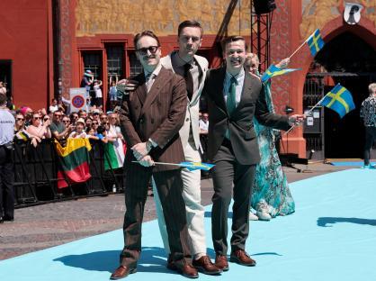 Three men representing Sweden at the Eurovision Song Contest's Turquoise Carpet ceremony.